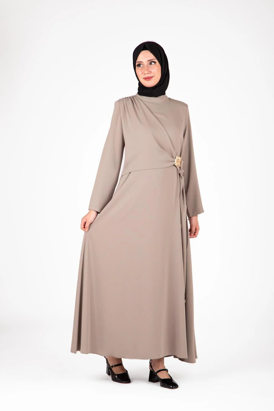 Woman wearing a beige dress with a black hijab on a white background