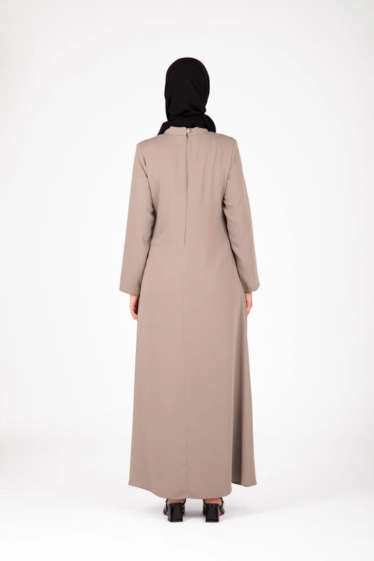 Person wearing a beige abaya and black hijab on a white background